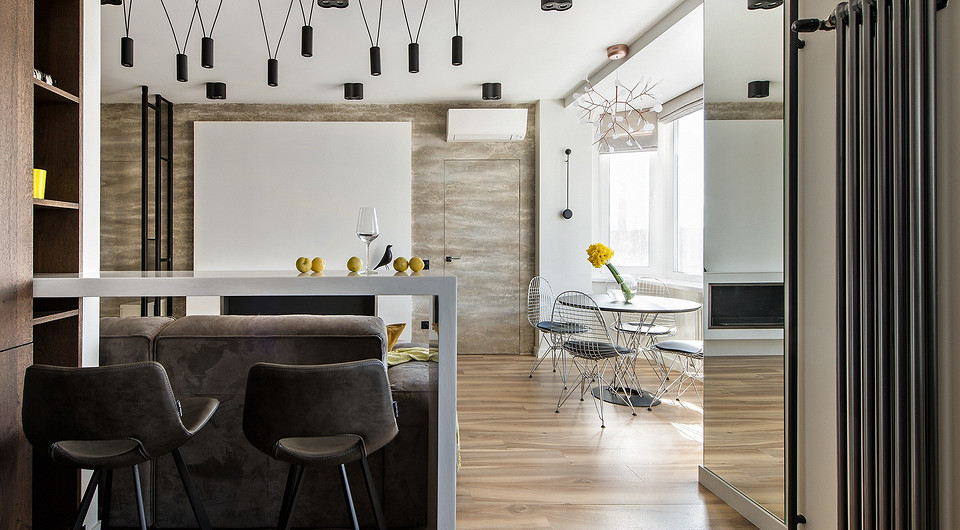 В дизайне студии исходили из функциональных задач: столовая группа и люстра над ней почти прозрачны, биокамин и экран для проектора — в композиционном центре