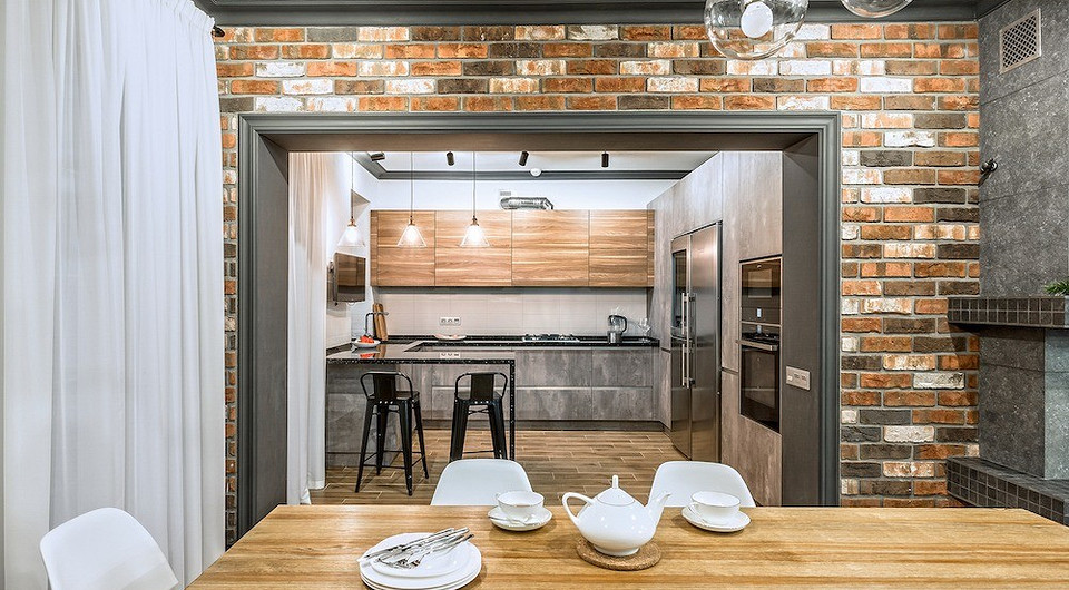 Часть кухонных фасадов оформлена имитацией бетона, другая — деревом, при этом панели оснащены механизмом открывания push-to-open. Всю техническую начинку, в том числе и винный шкаф, встро...