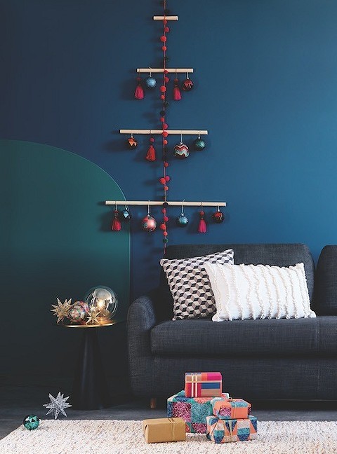 Как вариант, аналог новогодней ёлки может перекочевать на стену. Для его создания пригодятся деревянные палочки, нарядные подвески и гирлянды из пумпонов. А из оставшихся разноцветных сте...