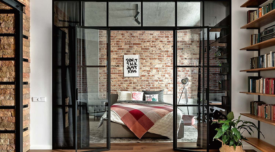 За изголовьем кровати, чтобы примыкание штукатурки под бетон и старинного кирпича выглядело аккуратнее, из ГКЛ выполнили узкий короб L-образной формы. По нижней линии «графемы» проложили...