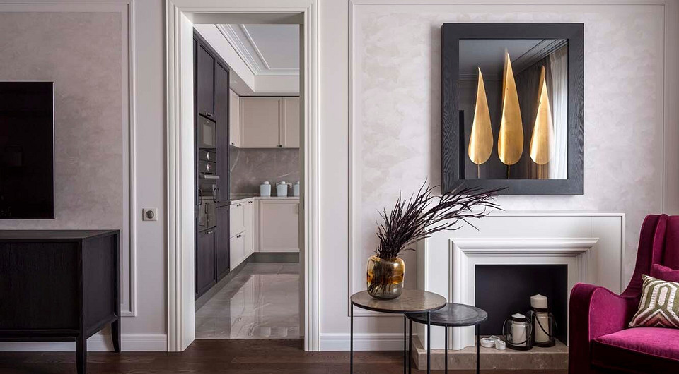 Проход в кухню фланкируют два разнородных объекта — слева от него помещена невысокая протяжённая тумба на изящных ножках, служащая опорой для ТВ-панели с большой диагональю, справа...