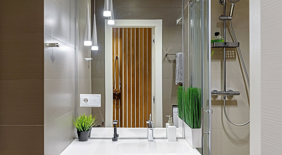 Реечную вешалку в прихожей прикрепили точно напротив дверного проёма ванной, чтобы композиция смотрелась цельно. Конусы потолочных светильников практично и оригинально вписались в мизансц...