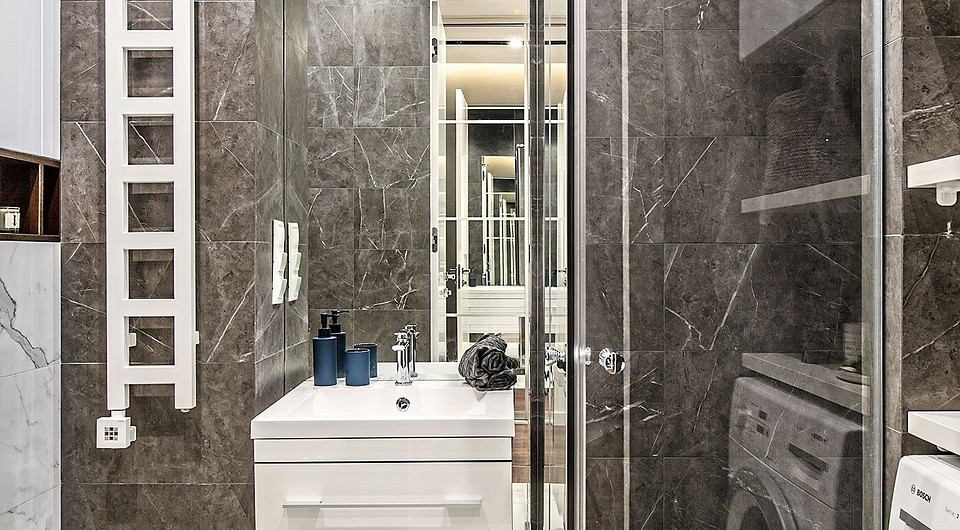 Ванную комнату одели в керамогранит, с удивительным реализмом воспроизводящий оттенки и рисунок прожилок белого и серого мрамора. Сэкономить площадь удалось с помощью душевой кабины в стр...