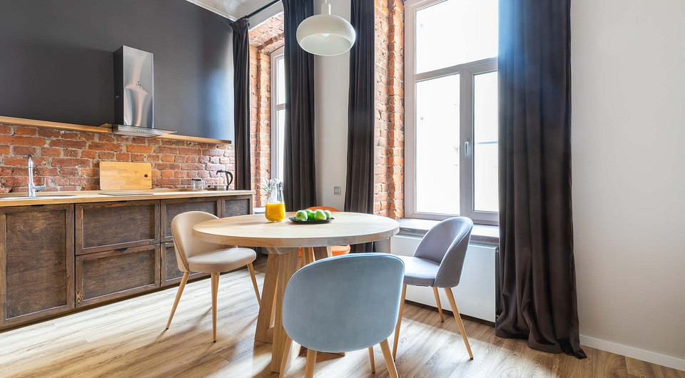 Обнажённые кирпичные поверхности стилистически объединяют все функциональные зоны. В дизайне кухонной мебели присутствует эклектика: форма фасадов — классическая, с филёнками, а ручки при...