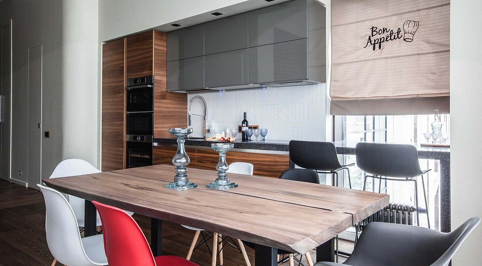 Рядом с меньшим окном студии обустроена кухня, а вплотную к окну — барный стол, объединённый с кухонной столешницей. Белоснежный фартук из плитки с тонким рельефом вылядит воздушно...