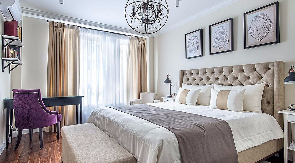 Обстановка спальни лаконична, помимо широкой кровати с высокой стёганой спинкой, тумбочками и скамьёй с мягкой обивкой здесь маленький туалетный стол с удобным креслом .