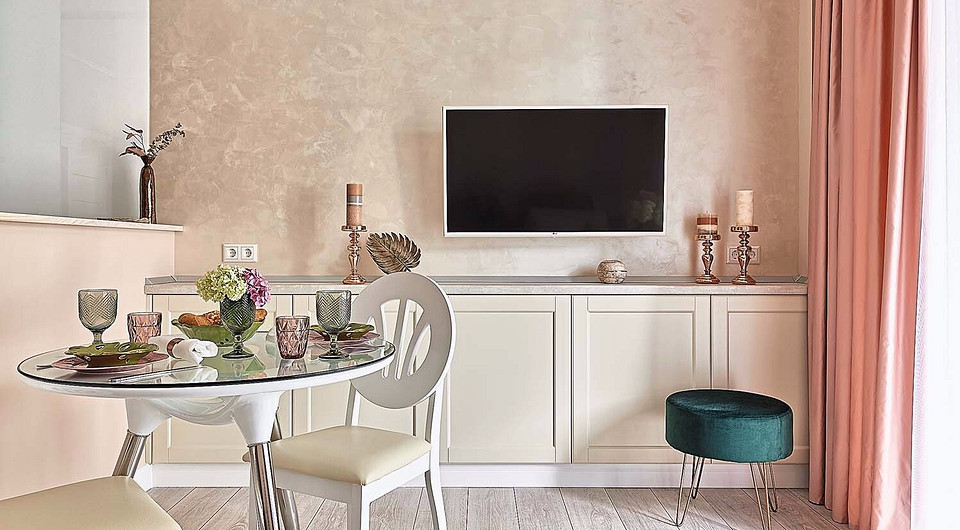 Обеденная зона сформирована круглым столиком с парой стульев. Перегородку между кухней и гостиной можно использовать в качестве барной стойки.