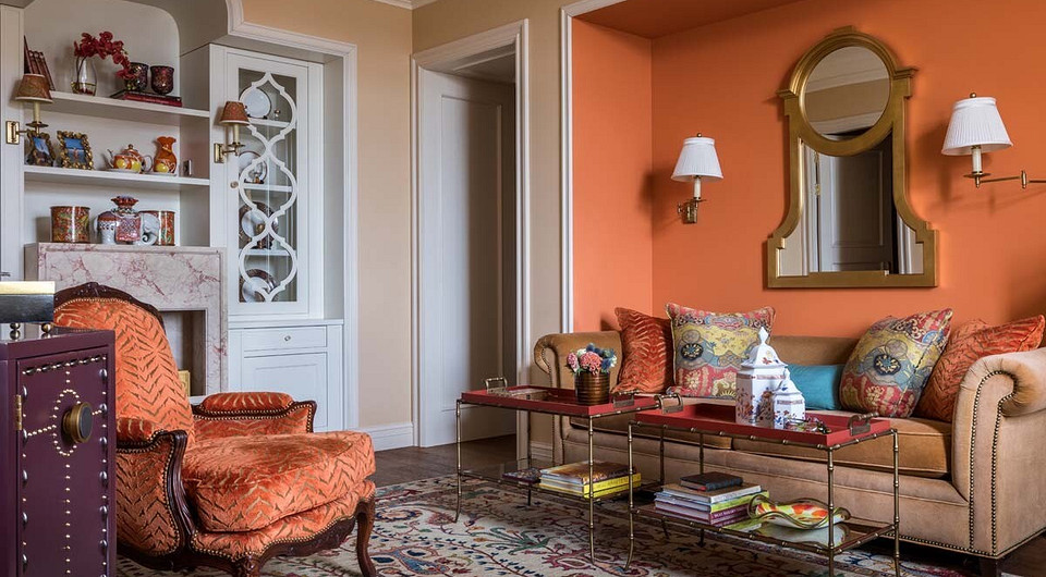 Все части ниши, в которую частично вписан диван, окрашены в сочный, хоть и приглушённый сложными холодноватыми оттенками оранжевый. Он контрастирует с более лёгким, бежевато-сливочным тон...