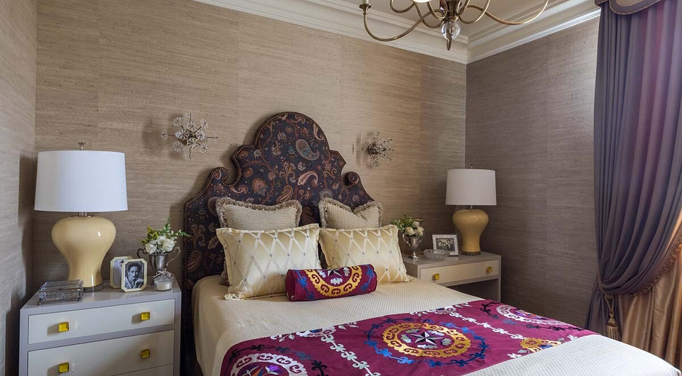 Стены спальни оклеены ткаными обоями с вкраплениями соломки, фигурная спинка кровати обита тканью с фантазийным узором, дизайн тумбочек современный и эффектно оттеняет восточные мотивы те...