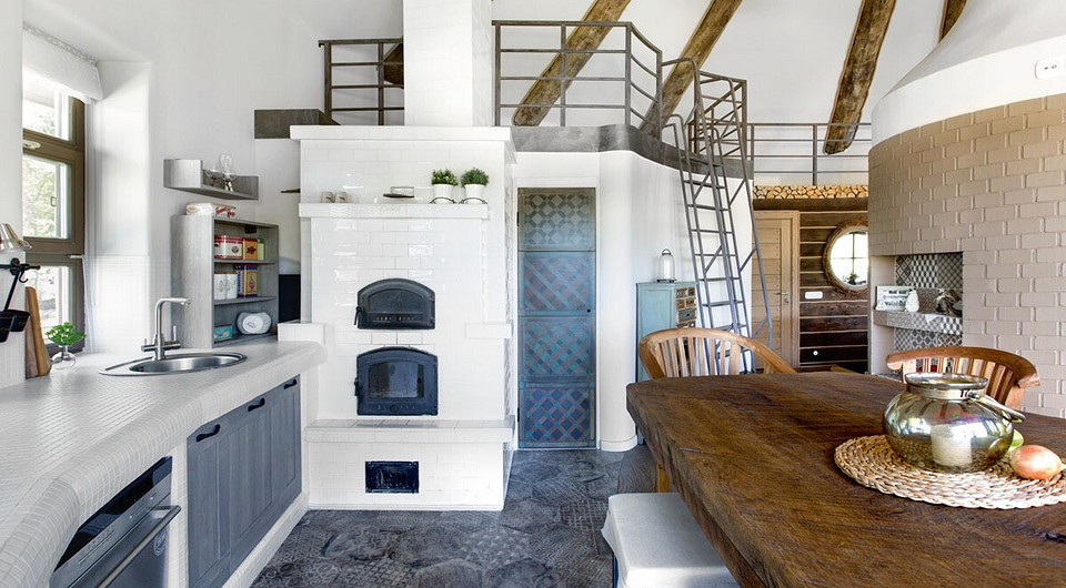 Каркас кухни сложили из пеноблоков вдоль округлой стены. В полученные ниши встроили готовые мебельные модули, столешницу выложили мозаикой. Утилитарное дополнение — русская мини-печь.