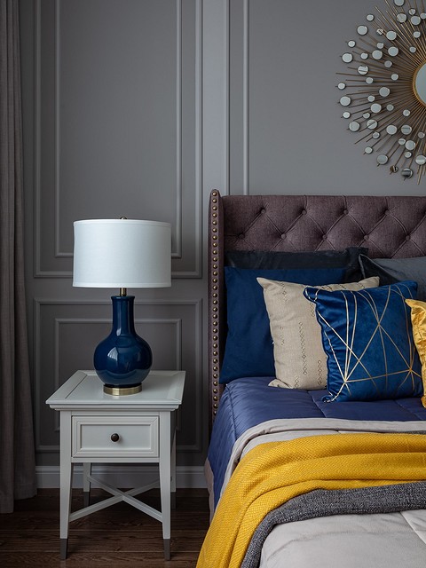 Холодный оттенок стен и мебели дополняют контрастные золотые акценты (на ковре, подушках, в декоре над кроватью).