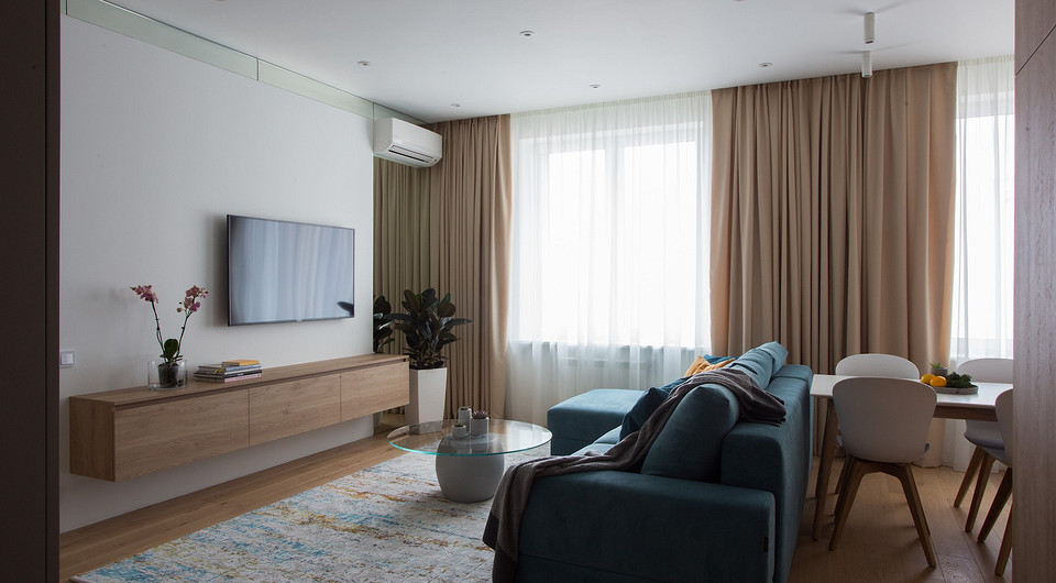 Прием с зеркалами применили и на потолке — в гостиной верхняя часть стены оформлена зеркальной полосой, которая создает эффект парящего потолка.