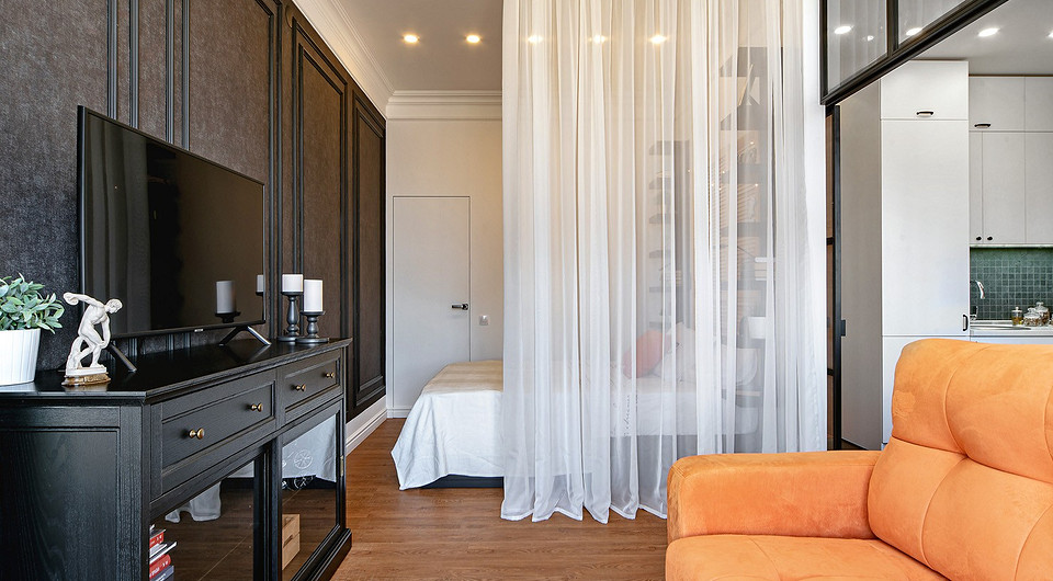 Шторы на окна сшиты из ткани с фактурой льна; перегородка между гостиной и спальней представляет собой полупрозрачный тюль.