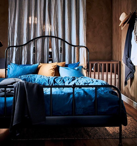 В комнате, где молодые родители живут вместе с маленьким ребенком, взрослая кровать установлена таким образом, что детская кроватка оказывается за изголовьем. И разделяют эти зоны гардины...