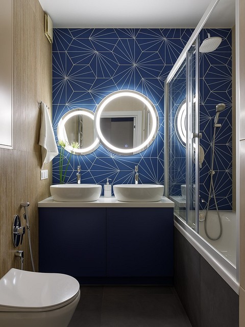 В санузлах в качестве общего света использовали споты, а дополнительный сценарий решен подвесными светильниками в гостевом санузле и подсветкой зеркала — в ванной комнате.