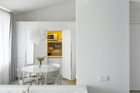 Квартира архитекторов: белый интерьер с кухней в шкафу и спальней на антресоли 