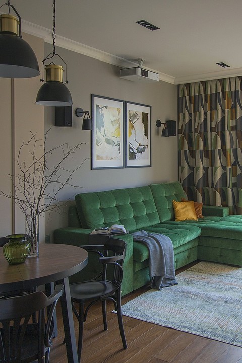Центральный элемент гостиной — диван травянисто-зеленого цвета. В поддержку ему гардины с предельно графичным рисунком. Объединяющие детали композиции — картины.