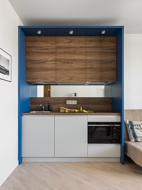 Кухня — очень компактная и необычная. Она встроена в своеобразный «бокс» синего цвета. Шкафов немного, но они вместительные. В нижний ряд встроена техника — маленький холодильник, микрово...