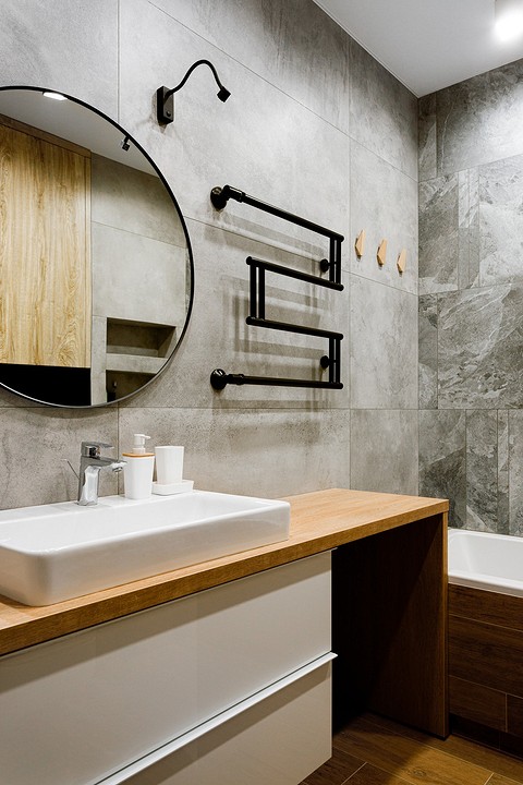 Стены ванной комнаты облицованы керамогранитом, фактура поверхности которого детально воссоздает обработанный вручную бетон. Отделка из крупноформатных плиток размерами 60х60 и 60х120 см...