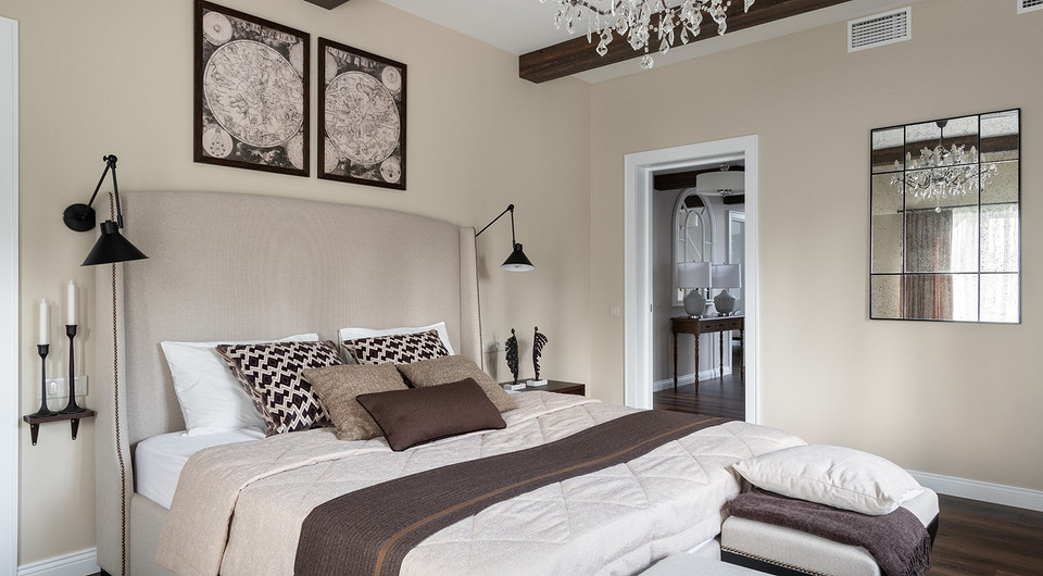 В хозяйской спальне находится большая кровать с высоким изголовьем. Симметрия пространства подчеркнута парными светильниками и парным стеновым декором. В отделке предпочтение отдано бежев...